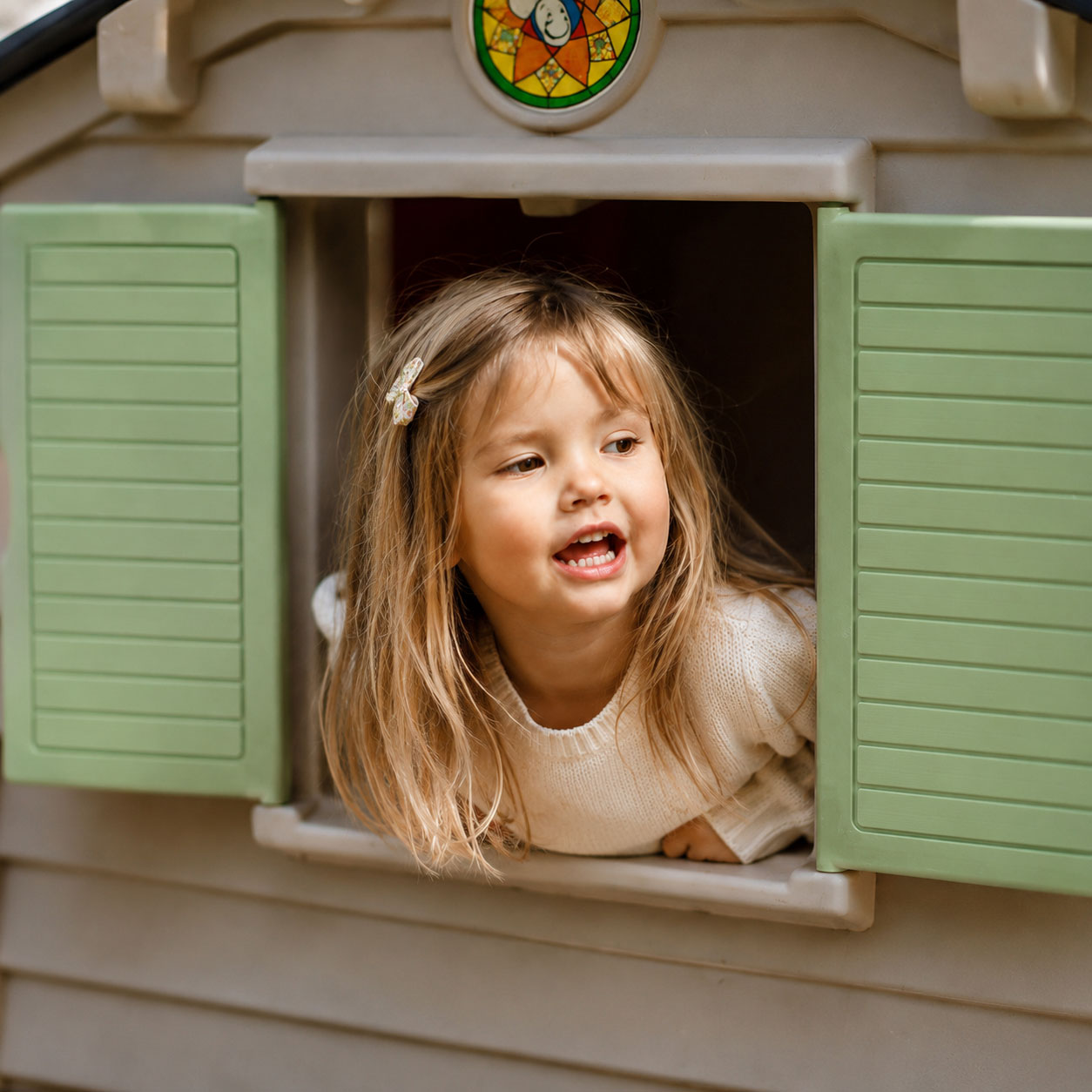 A child standing near the window of a playhouse